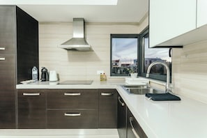 A modern kitchen with dark cabinets, a stainless steel range hood, a window with a view, and a sink. - Best Houses 23 - Surf & Chill Apartment Baleal (Ferrel)
