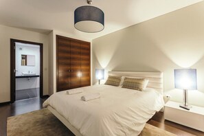 A hotel room with a large bed, a wardrobe, a bedside table with a lamp, and a bathroom visible through an open door. - Best Houses 23 - Surf & Chill Apartment Baleal (Ferrel)