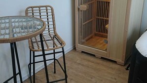 Una stanza con un tavolo in vetro, sedie in vimini, una porta in legno e un piccolo armadietto di legno.