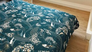 Camera da letto con lucernario, letto con copripiumino floreale, comodino con lampada e testiera scura.