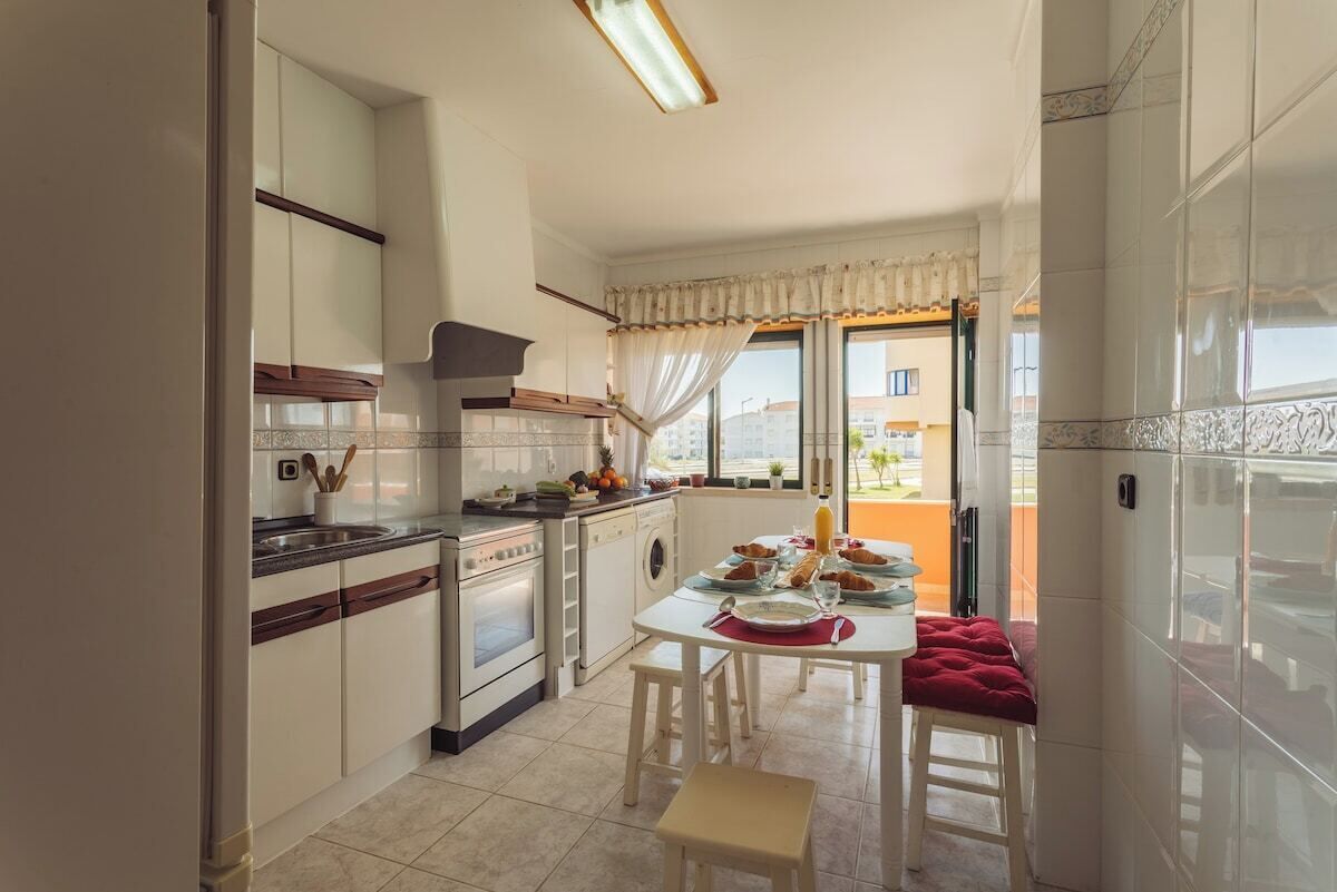 A compact kitchen with a dining area, a view through the window, and a red bench.