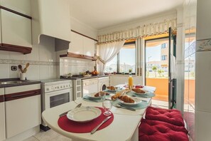 A kitchen with a dining table set for breakfast, a window with curtains, and a view of buildings outside. - Best Houses 18 - Typical Portuguese Apartament (Consolação)