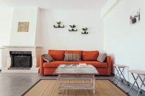 Una sala de estar con un sofá, una mesita de centro y tres estantes fijos en la pared con plantas.