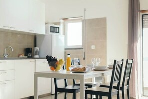 Une cuisine moderne avec des meubles blancs, une table à manger avec des chaises et des aliments pour le petit-déjeuner.