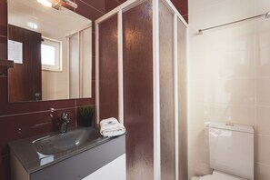 Et badeværelse med vask, spejl og toilet.