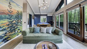 A room with a green sofa, a pool table, and a mural of a landscape. - Bluewood Escape: Sauna, Hot Tub, Game Room (Tobyhanna)