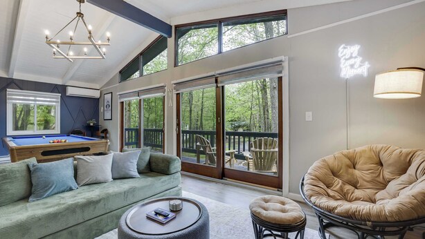 A spacious living area with a pool table, a comfortable sofa, a round ottoman, and a cushioned chair. - Bluewood Escape: Sauna, Hot Tub, Game Room (Tobyhanna)