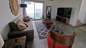 Ein Wohnzimmer mit einer Couch, einem Couchtisch, einem Fernseher und einem großen Fenster mit Blick.