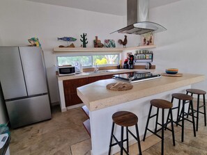 A modern kitchen with a central island, bar stools, a refrigerator, and decorative items on the wall. - House with Private Pool15 min Apt 20 MIn Hotel Zone (Cancún)