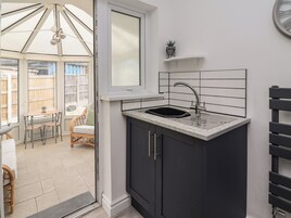 Una cocina compacta con un lavamanos integrado, armarios oscuros y ventana con vistas a un patio.