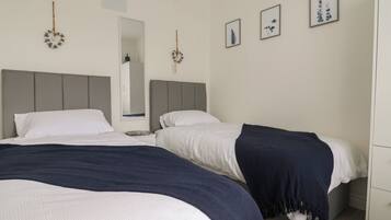 Un dormitorio con dos camas, una mesita de noche, un espejo y decoración en la pared.