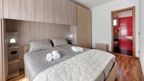 Un dormitorio con cama, mesitas de noche, un espejo y un armario.