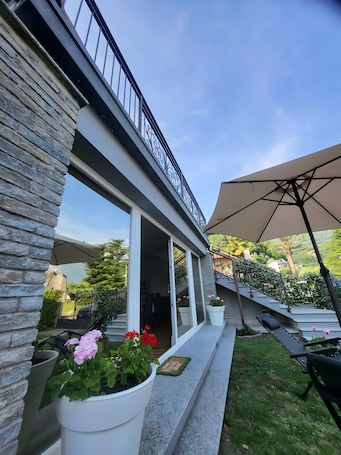 A modern building with a stone facade, large windows, and a balcony with outdoor seating.. Aphrodite's Garden – Central Yet Peaceful Apartment Close to Lake and Beaches