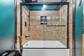 Une salle de bain moderne avec une douche à parois de verre, une baignoire blanche et un mur recouvert de carreaux.