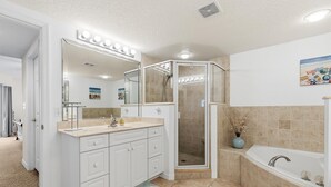 A bathroom with a vanity, a shower enclosure, a bathtub, and a mirror with lights. - Oceanwalk 15-403 (New Smyrna Beach)