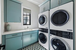 A laundry room with two front-loading washing machines, a sink, and teal cabinets. - Casa Amor|Easy Beach Access|Private Pool|Golf Cart (Seagrove Beach)