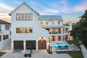 A two-story house with a large garage, a swimming pool, and a covered patio area. - Casa Amor|Easy Beach Access|Private Pool|Golf Cart (Seagrove Beach)