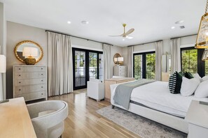A modern bedroom with a large bed, a desk, a chair, and a dresser. There is a balcony with a view of greenery. - Casa Amor|Easy Beach Access|Private Pool|Golf Cart (Seagrove Beach)