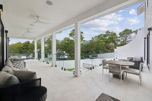 A spacious covered patio with a dining area, seating, and a view of the surrounding trees. - Casa Amor|Easy Beach Access|Private Pool|Golf Cart (Seagrove Beach)
