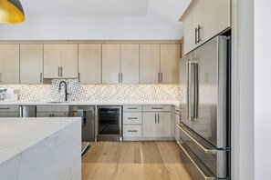A modern kitchen with light wood cabinets, stainless steel appliances, and a patterned backsplash. - Casa Amor|Easy Beach Access|Private Pool|Golf Cart (Seagrove Beach)