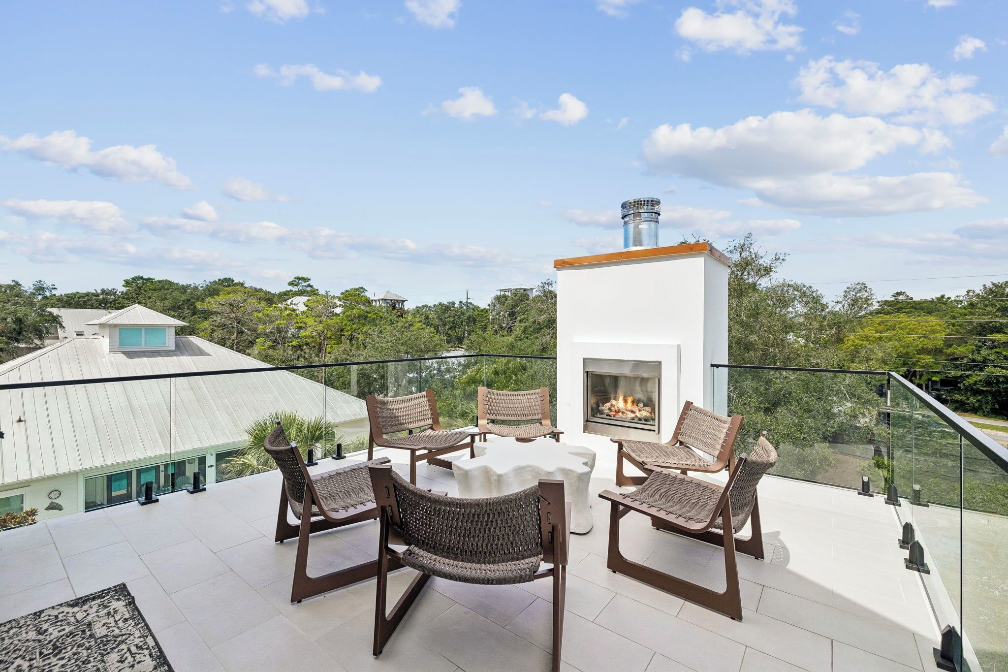A rooftop terrace with a fireplace, outdoor seating, and a view of the surrounding landscape.