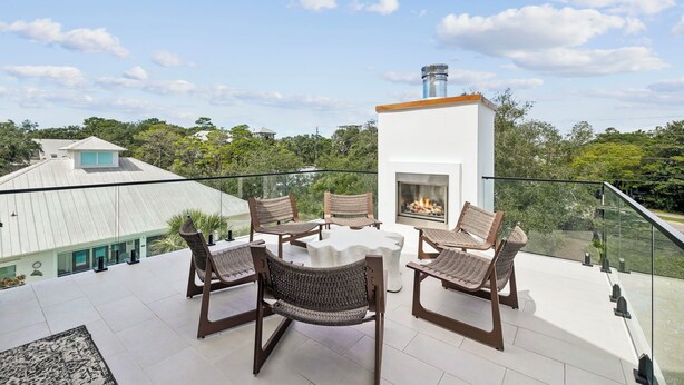Una terraza en la azotea con chimenea, mobiliario exterior y vistas al paisaje circundante.