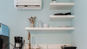 Una cocina con cafetera, lavamanos y un armario.