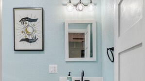 Un baño con inodoro, lavabo, tocador y una obra de arte enmarcada en la pared.