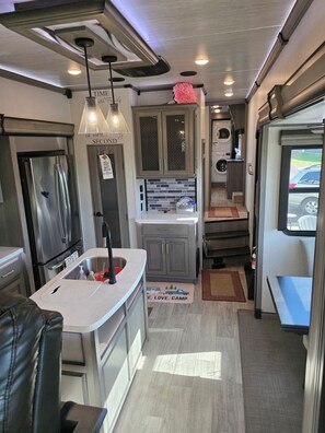 A compact kitchen with a refrigerator, sink, and cabinets.