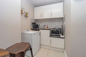 A compact kitchen with white cabinets, a microwave, a coffee maker, and a small countertop. - Central Ground Floor Studio - By Sea
MID10 (Brighton and Hove)
