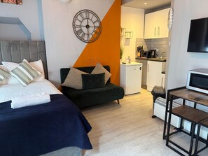 A modern room with a bed, a sofa, a small kitchen, and a TV. - Central Ground Floor Studio - By Sea
MID10 (Brighton and Hove)