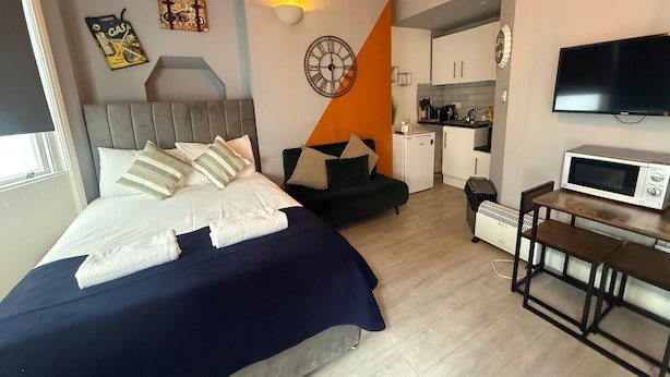 Een kleine hotelkamer met een bed, een slaapbank, een kitchenette en een televisie.
