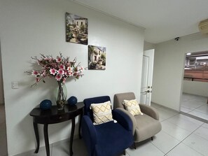 A living room with a sofa, armchairs, a small table with a vase of flowers, and two wall-mounted pictures. - The Diamond Hotel (San Salvador)