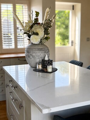 A kitchen island with a vase of flowers, a candle, and a glass jar. - The Old Cowshed - with free parking! (Marchington)
