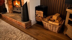 Een gezellige kamer met een open haard, een houtkachel en een stapelhout.