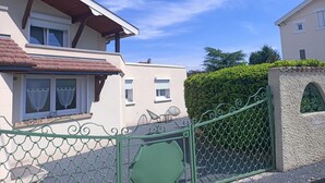 Um edifício residencial com telhado de telhas vermelhas, varanda e portão de metal verde.