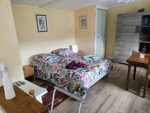 A bedroom with a bed, a wooden desk, a chair, a wardrobe, and a nightstand.