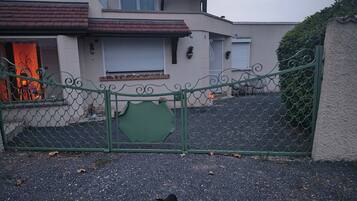 A residential building with a gated entrance, a paved driveway, and a visible garage door.