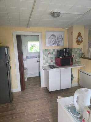 Cocina compacta con microondas, hervidor y cafetera sobre la encimera.