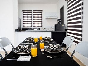 A dining table set with black and white patterned bowls, plates, and glasses of orange juice. - Beautiful house 2 bedroom wifi tv (Caucel)