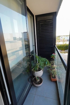 Ein Balkon mit Glastür, Blumentöpfen und Blick auf Gebäude.