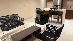 Une cuisine moderne dotée d’un réfrigérateur en acier inoxydable, de meubles en bois et d’un coin bar avec des chaises noires.