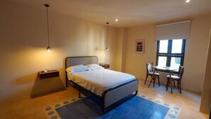 Een slaapkamer met een bed, nachtkastje, stoel, bureau en raam.