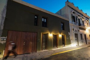 A street view of a building with a large wooden door, a series of windows, and a balcony with railings. - Beautiful studio in the heart of the city. (Merida)
