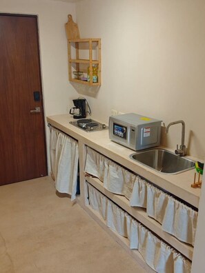 A small kitchenette with a microwave, coffee maker, and a sink. - Beautiful studio in the heart of the city. (Merida)