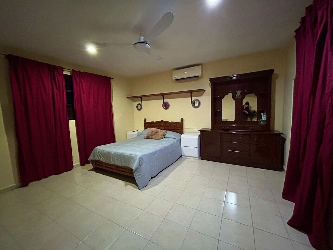 A bedroom with a bed, a nightstand, a dresser, a ceiling fan, and a wall-mounted air conditioner.