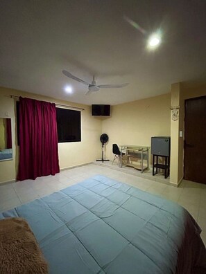 A bedroom with a bed, a ceiling fan, a TV, a desk, and a chair. - Departamento en Xcumpich 2 Recamaras (Merida)
