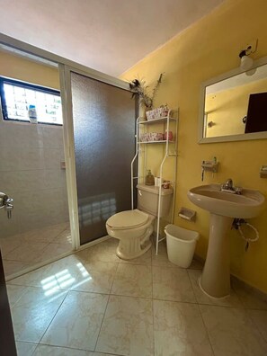 A bathroom with a toilet, sink, and shelves. - Departamento en Xcumpich 2 Recamaras (Merida)