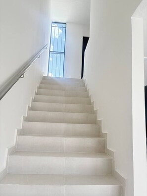 A white staircase with a handrail, leading to a room with a window. - Casa 5 minutos del Foro GNP Américas (Mérida)