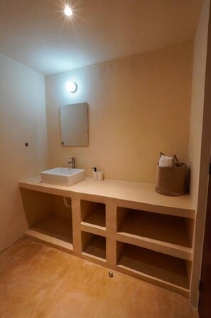 Ein Badezimmer mit Waschbecken, Spiegel, Handtuchspender und Ablagefläche mit einer Tasche.